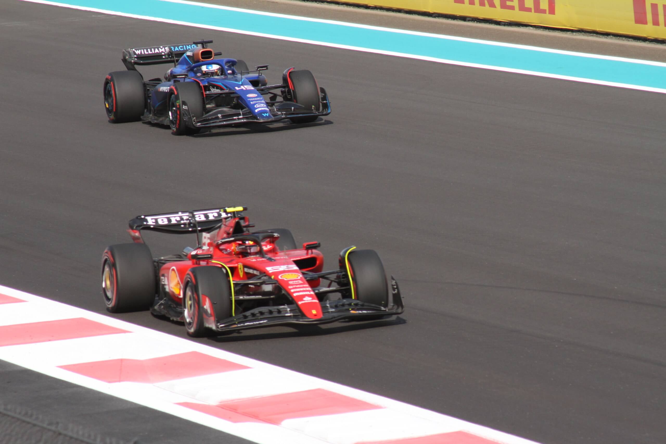 Une voiture formule 1 bleue tente de dépasser une voiture formule 1 rouge Ferrari