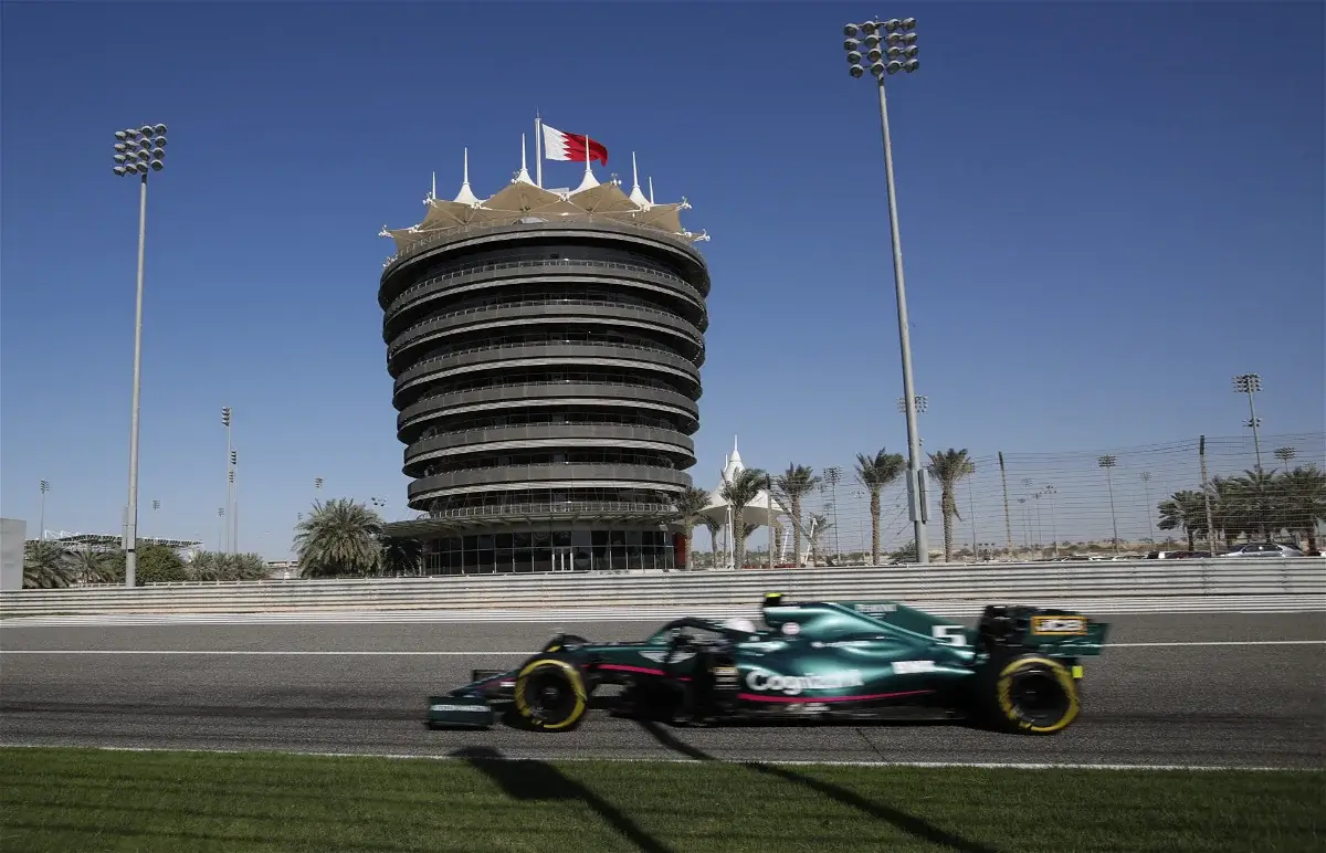une voiture de formule 1 passe devant une tour sur lequel est planté un drapeau
