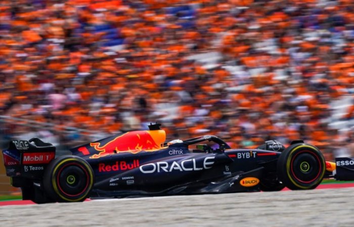 Une voiture de formule 1 red bull passe devant une tribune remplie de gens habillés en orange