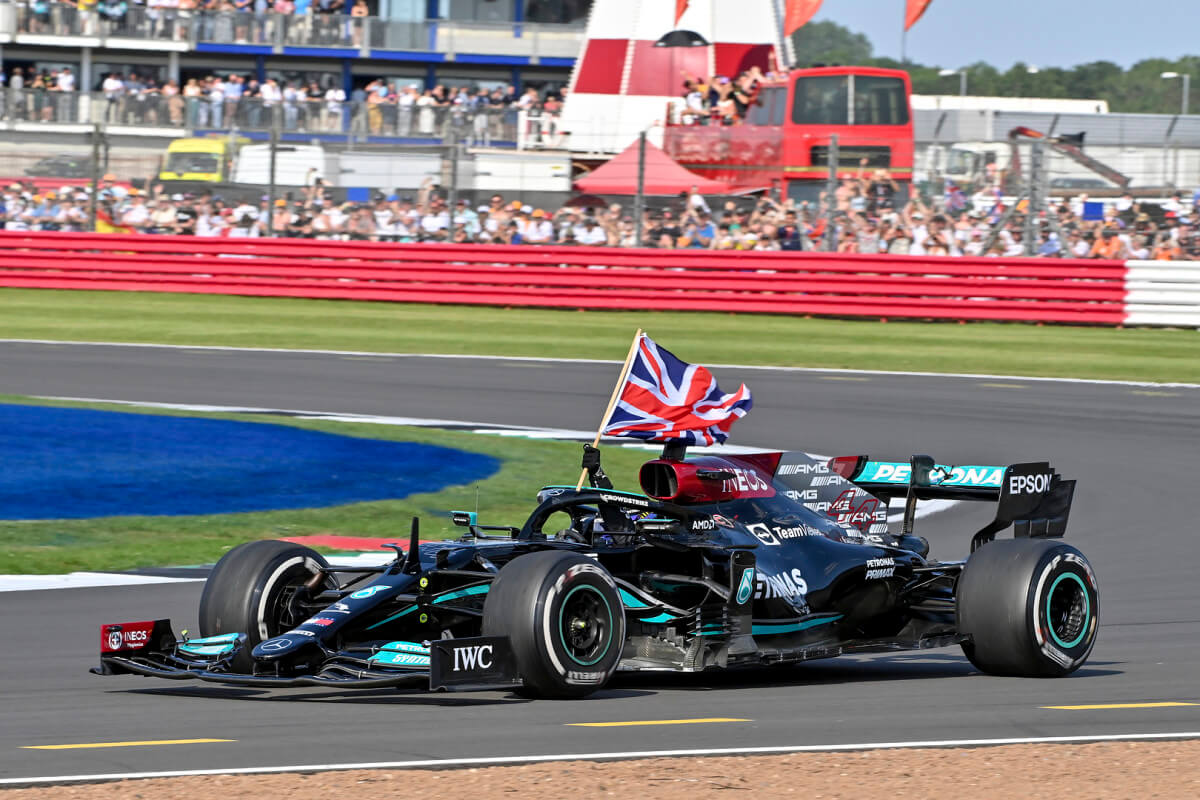 une voiture de formule 1 avance sur la piste en portant un drapeau du Royaume-Uni