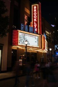 a theater marquee lit up at night with people walking by